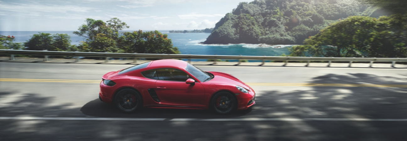 2019 Porsche 718 Cayman in red driving along a coastal highway